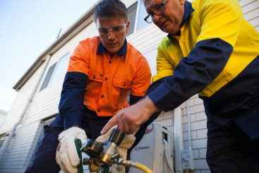 Teacher helping student hands on in our air conditioning course Brisbane