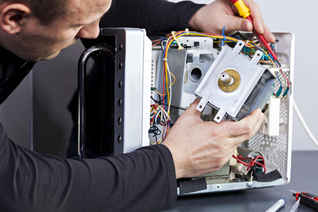 Man servicing microwave oven | Featured image for Appliance Servicing and Repair - Restricted Electrical Licensing Course by Get Skilled Training