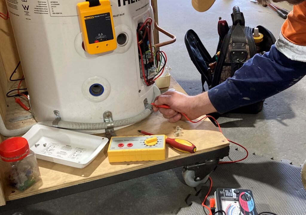 Technician testing electronics of gas appliance | Featured image for Gas Appliances/Equipment Limited to 250Vac – Restricted Electrical Licence Course by Get Skilled Training.
