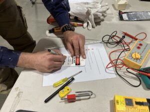 Man writing on a do not operate this equipment tag.