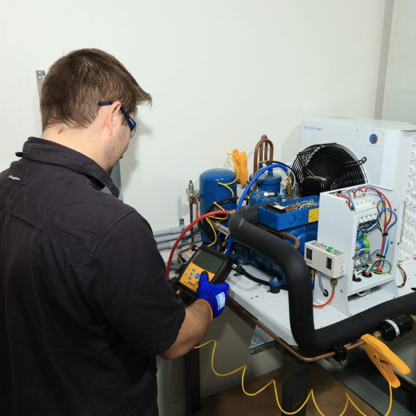 Man checking pressure measurements on refrigeration unit | Featured image for Certificate III in Refrigeration & Air Conditioning on Get Skilled Training