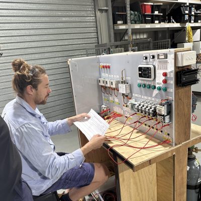 Man working at a desk with instructions and numerous electrical wires