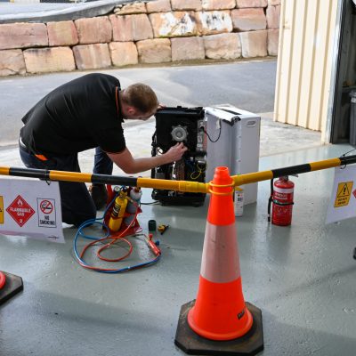 Man installing gas fittings behind safety barrier | Featured image for Gas Work License Hydrocarbon page on Get Skilled Training.