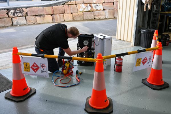Man installing gas fittings behind safety barrier | Featured image for Gas Work License Hydrocarbon page on Get Skilled Training.
